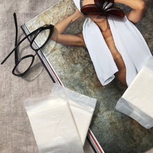 Carica l'immagine nel visualizzatore di Gallery, Due assorbenti Queesy compostabili ripiegati in bustina biodegradabile, poggiati su un libro.