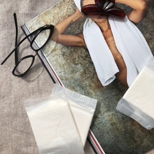 Carica l'immagine nel visualizzatore di Gallery, Due assorbenti Queesy compostabili ripiegati in bustina biodegradabile, poggiati su un libro.