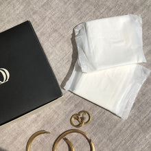 Carica l'immagine nel visualizzatore di Gallery, Due assorbenti Queesy ripiegati singolarmente in bustina biodegradabile, il lato superiore della confezione Queesy, gioielleria.